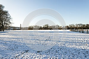 A view to a large arbour and McGrigor obelisk from a large lawn covered by snow in Duthie park, Aberdeen, Scotland