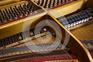 View to the mechanics inside an older grand piano, hammer from below and damper from above on the strings of the acoustic musical