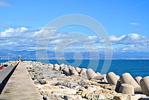 A view to Mediterranean sea, a lighthouse with breakwaters and Torremolinos from a pier