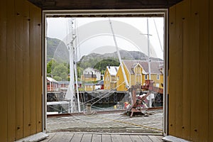 View to Nusfjord harbor through a orange gate. Nusfjord is a small fishing village on Lofoten Islands, Norway