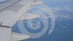 view to plane wing\'s flap while aeroplane flying ovet cloud in sky above Phuket in morning time, holiday vacation travel