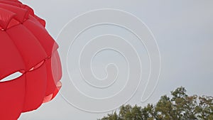 view to red parachuter paragliding umbrella with wind blowing against clear blue sky in summer holiday vacation time