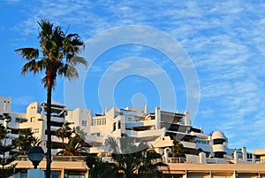 A view to a resort building at the seashore with palm trees on sunny evening, Torremolinos