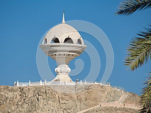 View to the Riyam Park monument dome through the palm leaves. Muscat, Oman.