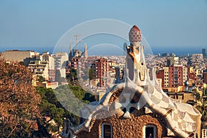 View to the roof and pinnacle of the Gatekeeper House of Park Guel and panorama of Barcelona city.