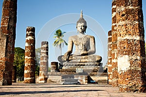 View to the ruins and sitting Buddha statue at Wat Mahathat temple in Sukhothai Historical Park