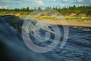 View to the beach of the Baltic sea on sunny summer day from inside a barrelling wave photo