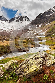 View to snow on Caucasus mountains over clear water stream near