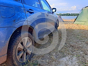 View to suv offroad car wheel on river shore near camping zone