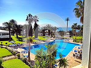 view to a swimming pool with sunshade and palm trees