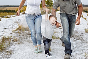 View on toddler. Mother, father hold hands son enjoy nature and walk in the mountains. Young family spending time together on