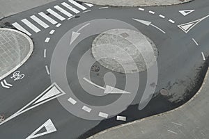 View from top on empty traffic circle or roundabout road with white arrows, crosswalk and other road signaling or marking