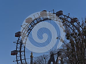 View of the top of famous Ferris wheel at amusement park Wurstelprater in Vienna, Austria with gondolas and bare trees.