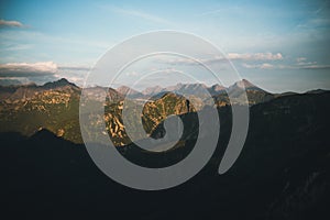 View from the top of Giewont Mountain on cliffs and mountains at sunset with a big shadow from the mountain itself