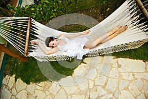 View top. girl in white dress lying in hammock