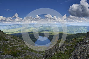 view from the top of the mountain to the blue lake surrounded by coniferous forest and mountain range