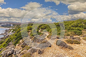 View from top of mountain to hotels standing on shores of Mediterranean sea against background of blue sky with white clouds.