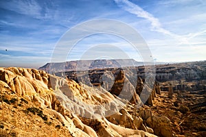 View from top place on the strange landscape in the Cappadocia valley with yellow mountains, rocks and hills and blue sky with