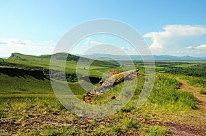 A view from the top of a rocky hill at a gap in the resolved ancient wall going along the slopes of a hollow hill