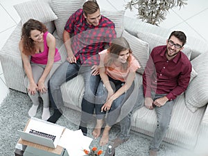 Triumphant group of friends laughing while sitting on the couch in the living room