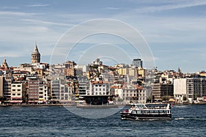 View of a tour boat on Golden Horn part of Bosphorus in Istanbul. Galata tower and Beyoglu district are in the view.