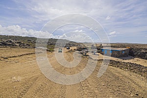 View of tourists off-road cars on sandy desert road merging with pale blue sky on horizon.