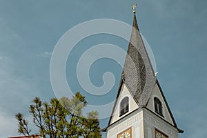 View towards the belltower of local church in Reith, close to Kitzbuhel in Austria on a overcast summer day