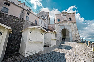 View towards the main entrance gate tower of Motovun city with visible stalls for souvenirs that are still closed. Sunny blue sky