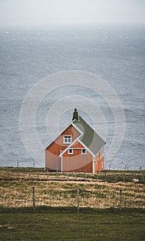 View towards orange house on Akraberg lighthouse at Suduroy island at summer, Faroe Islands.