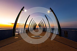 View towards a summer sunrise over the ocean through a deserted pier