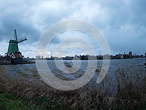 View of the town from the other side of the river next to windmill behind the grass