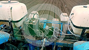 View from tractor cab. Closeup of Tractor seeder, pneumatic sowing machine, sowing of corn, Maize in soil, in field