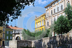 View of traditional colorful croatian buildings with the Arch of the Sergii at the background, in the old town of Pula, Croatia