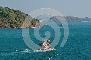 A view of traditional fishing boats heading out to sea of the island of Phuket, Thailand