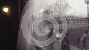 The view from the train window, the rain on the window of the car window. People walk along the railway. Train railway