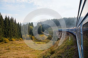 View from the train window at the sunlit village. Carpathians