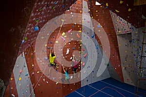 View of trainer and athletes rock climbing in gym