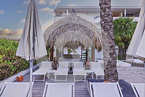 View of a tranquil beach spot with palm leaf umbrellas providing shade for a large leather sunbed at a Caribbean Sea hotel.