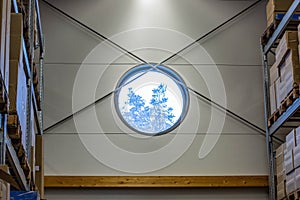 View on trees through round window of warehose. Beautiful backgrounds