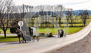 View of Two Amish Horse and Buggies Traveling Down a Countryside Road Thru Farmlands