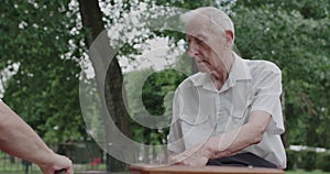 View of two elder friends playing chess game and pushing the buttons of clock