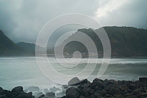 The view of two hills lined with dense and green trees located on the beach which has clear and refreshing water. Photos were take