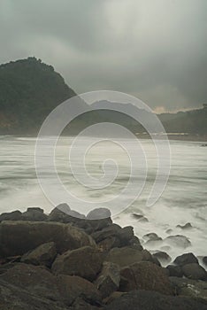 The view of two hills lined with dense and green trees located on the beach which has clear and refreshing water. Photos were take