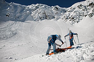 view of two men skiers in ski suits and helmets putting on hiking equipment for climbing