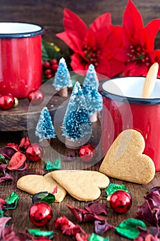 View of two red mug, heart-shaped gingerbread cookies and red Christmas decoration,