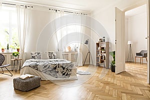 View at two rooms with white walls and herringbone parquet. A be