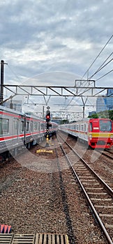 View of two trains passing back and forth at the station with a traffic light in the middle.