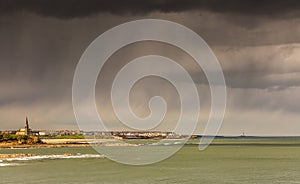 The view of Tynemouth, Cullercoats & Whitley Bay including St Mary`s Lighthouse taken from Tynemouth`s North Pier on a rainy day photo