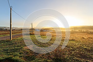 View of typical Alentejo landscape with Portuguese village in morning fog an rising sun at the Rota Vicentina hiking trail near