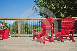 View of typical canadian red muskoka chairs on a wood deck photo